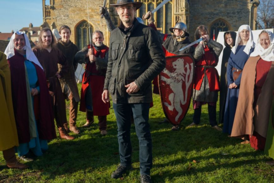 man stands surronded by people dressed in medival clothes